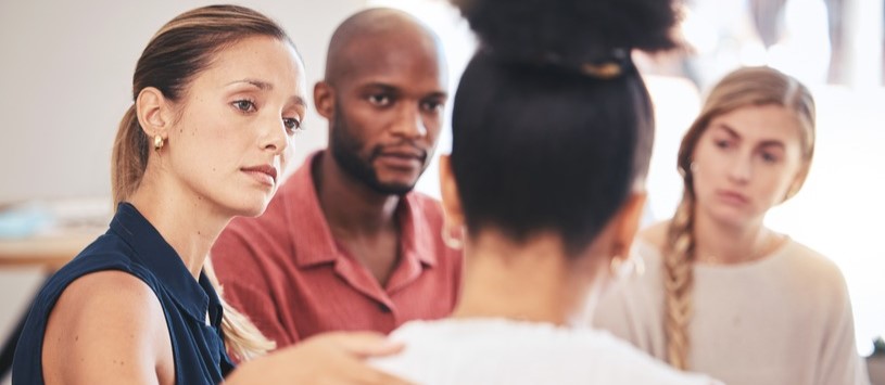 Human Services professional comforting a client in a group therapy setting.