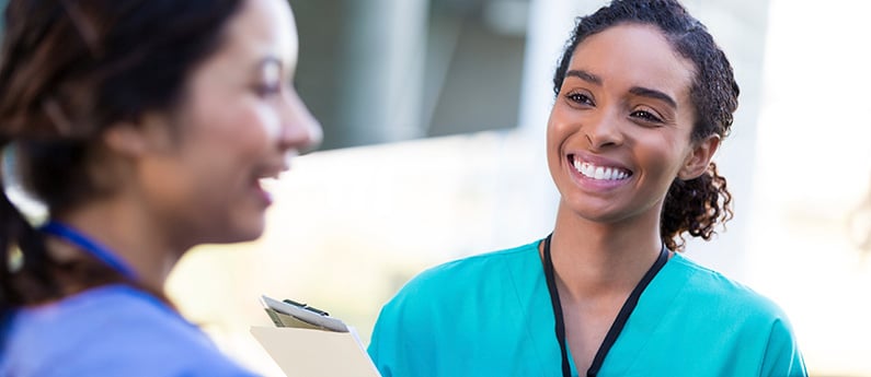 Two female Medical Assistant Specialists in scrubs working in a healthcare setting.