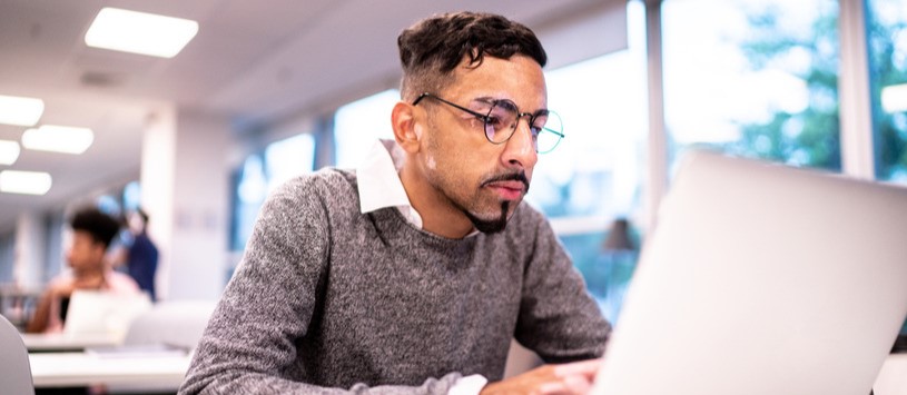 CW's Business Administration – Management online student working on a laptop.